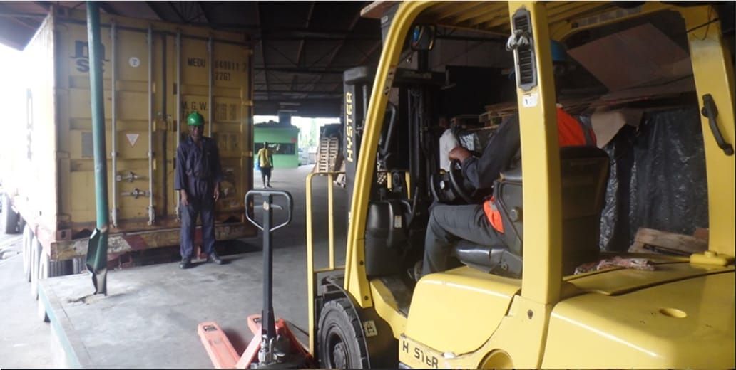 Forklift moving goods beside a shipping container